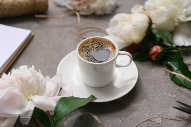 Arkaplanda şakayık çiçekleri olan bir fincan kahve, yakın plan.