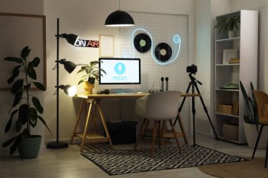 Podcaster 'ın atölyesinin içinde iş yeri, vinil diskler ve parlayan lambalar var.