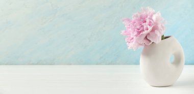 Mavi duvarın yanındaki masasında güzel şakayık çiçekli vazo, yakın plan.