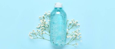 Bir şişe mikiler suyu ve mavi arka planda çiçekler.