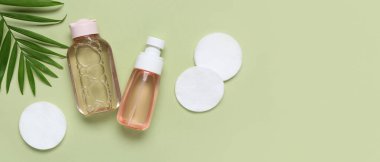 Su şişeleri, pamuk pedler ve yeşil arka planda yapraklar.