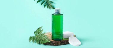 Bir şişe mikiler suyu, pamuk pedler ve turkuaz arka planda ahşap bir dilim, yakın plan.