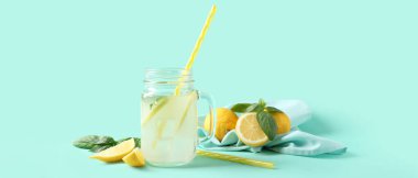 Turkuaz arka planda nane ve fesleğen yapraklı bir kavanoz taze limonata.