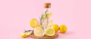 Pembe arka planda biberiyeli bir şişe taze limonata.