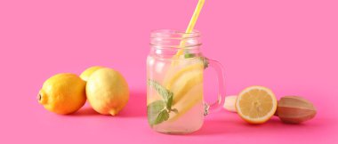 Mason kavanozu taze limonata, nane ve pembe arka planda limon.