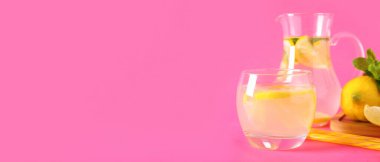 Bir bardak taze limonata ve pembe arka planda nane şekeri.