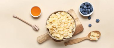 Lezzetli mısır gevreği, yabanmersini ve bal dolu bej arka planda.