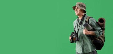 Dürbünlü ve yeşil arka planda sırt çantalı erkek gezgin ve metin için yer var