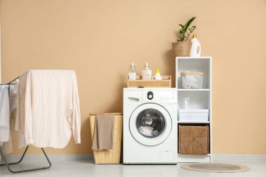 Çamaşır makinesi, sepet ve kurutuculu modern çamaşır odasının içi.