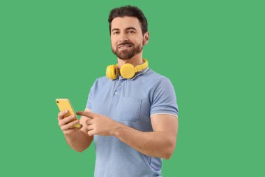 Yakışıklı adam cep telefonuyla yeşil arka plan üzerinde