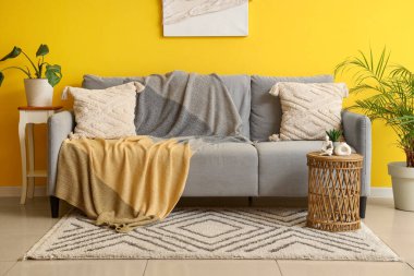 Oturma odasının içinde ekose, kahve masası ve çiçekli rahat bir kanepe.