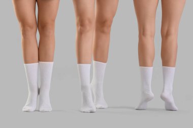 Gri arka planda şık beyaz çoraplı genç kadınların bacakları