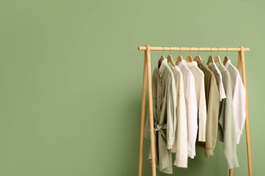 Yeşil duvarın yanında şık giysilerle dolu bir oda.