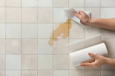 Beyaz fayansların üzerine kağıt peçeteyle kahve döken kadın.