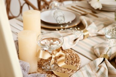 Odasında yanan mum ve bahar çiçekleri olan bir bardak su, yakın plan.