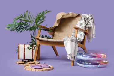 Bavullu koltuk, şişirilebilir yüzükler ve mor arka planda plaj aksesuarları. Yaz tatili kavramı