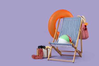 Bavullu iskemle, şişirilebilir yüzük, mor arka planda top ve plaj aksesuarları. Yaz tatili kavramı