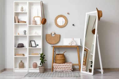 Oturma odasının içinde, raflar, aynalar ve ev dekorasyonu gri duvarın yanında.