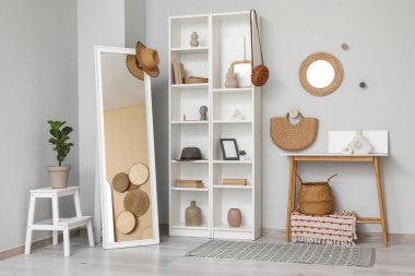 Oturma odasının içinde, raflar, aynalar ve ev dekorasyonu gri duvarın yanında.