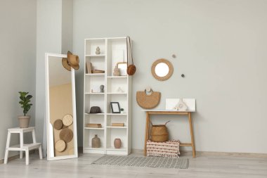 Oturma odasının içinde, raflar, aynalar ve ev dekorasyonu gri duvarın yanında.