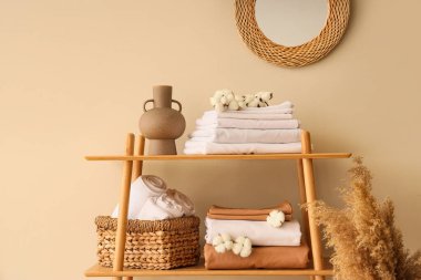 Raflar temiz yatak çarşafları, pamuk çiçekleri ve bej duvarın yanındaki ev dekoruyla dolu.