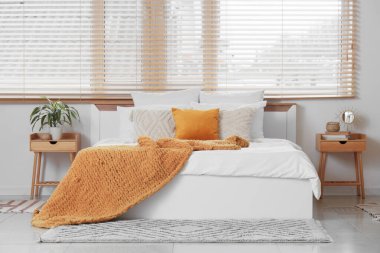 Yatak odasının içi. Büyük yataklı, komodinli ve penceresinde ahşap panjurlar olan.