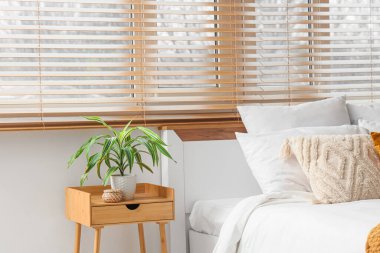 Yatak odasının içi, büyük yataklı, komodinli ve penceresinde ahşap panjurlar olan.