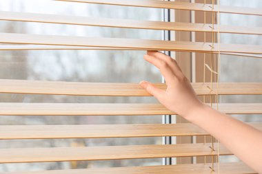 Evin penceresindeki tahta panjurların yanında kadın eli, yakın plan.