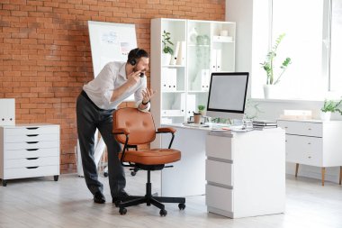 Kulaklığı ve boş bilgisayarı olan genç bir işadamı ofiste çalışıyor.