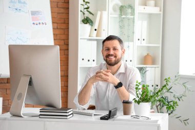 Ofisteki masada gülümseyen genç işadamı