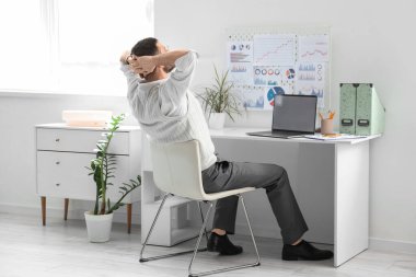 Boş dizüstü bilgisayarı olan genç bir adam ofiste oturuyor.