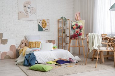 İçinde yatak, sehpa ve masa olan dağınık çocuk odası.