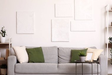 Gri kanepe, masa ve resimlerle dolu bir oturma odası.