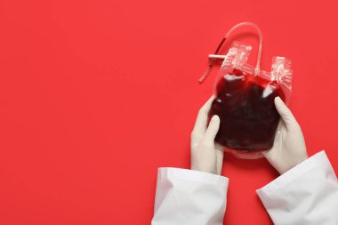 Kırmızı arka planda kan nakli için kan torbası olan kadın doktor elleri. Kan bağışı konsepti