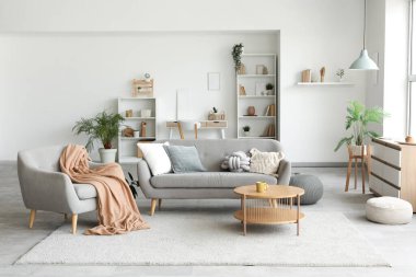 Oturma odasında kanepe, koltuk, raf ünitesi, sehpa ve tuvalet var.