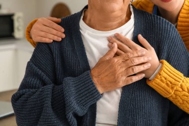 Genç bakıcı mutfakta yaşlı kadına sarılıyor, yakın plan.