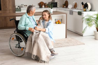 Ekoseyle kaplanmış genç bir kadın. Büyükannesi tekerlekli sandalyede.