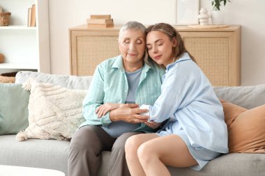 Torunuyla evde kanepede sarılan son sınıf öğrencisi bir kadın.