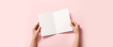 Pembe arka planda boş broşür tutan eller  