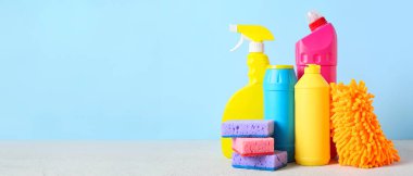 Mavi arka planda temizlik malzemeleri ve şişe deterjan, yakın plan.