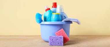 Temizlik malzemeleri ve bej arka planda bir şişe deterjan.