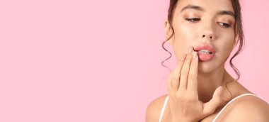 Pembe arka planda güzel dudakları olan genç bir kadın.