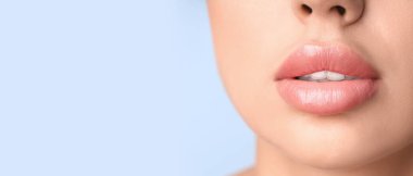 Açık mavi arkaplanda güzel dudakları olan genç bir kadın, yazı için yeri var, yakın plan.