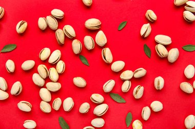 Lezzetli fıstıklar ve kırmızı arka planda yapraklar