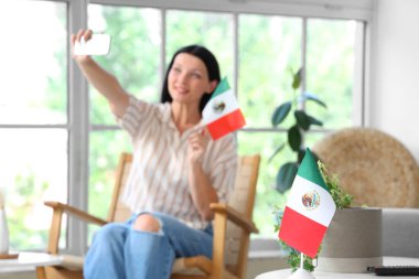 Meksika bayrağıyla evde selfie çeken genç bir kadın.