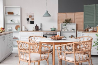 Mutfağın içinde yemek masası, tezgah ve ev bitkileri var.