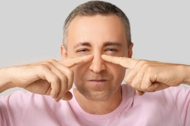 Gri arkaplanı işaret eden olgun bir adam.