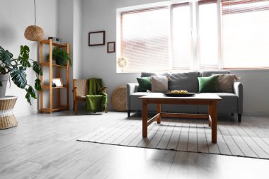 Oturma odasının iç tarafındaki ahşap sehpada limonlu rahat gri kanepe ve tabak.