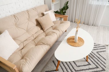 Modern oturma odasındaki rahat beyaz kanepe ve çiçek desenli kahve masası.