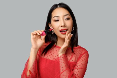 Gri arkaplanda ruj izi olan güzel bir Asyalı kadın.